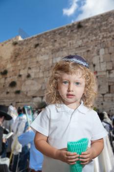 Autumn Jewish holiday Sukkot. The greatest shrine of Judaism is the Western Wall of the Temple. Lovely blonde boy with blue eyes in a skullcap