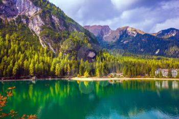 Green expanse of water reflects the surrounding mountains and forest. South Tyrol, Italy. Magnificent lake Lago di Braies. The concept of walking and eco-tourism
