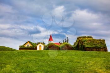 The village of houses covered with turf and grass. Church bell tower with red gabled roof. Ethnographic Museum-estate Glaumbaer, Iceland. The concept of the historical and cultural tourism