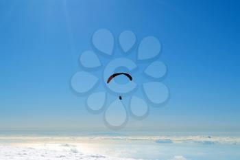 Paraglider flying over clouds in a summer day