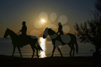Two riders riding during sunset on the seashore