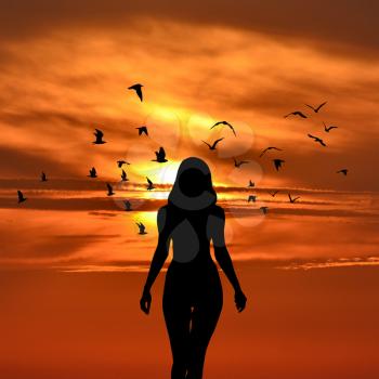 Silhouette of woman with birds flying around her on sunset