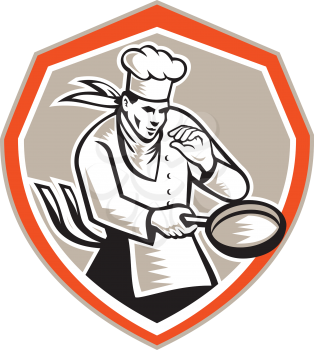Illustration of a chef cook holding frying pan set inside shield on isolated background done in retro woodcut style.
