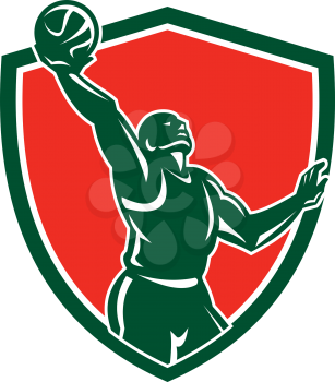 Illustration of a basketball player rebounding lay-up ball set inside shield crest on isolated background done in retro style.
