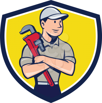 Illustration of a plumber wearing hat looking to the side arms crossed holding monkey wrench viewed from front set inside shield crest on isolated background done in cartoon style.