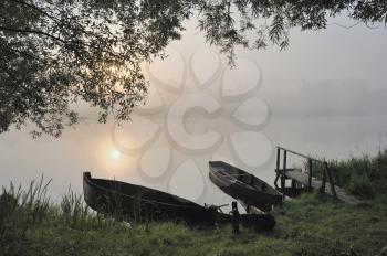 Royalty Free Photo of a Foggy Morning With Boats at the River's Edge