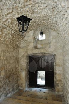 Royalty Free Photo of a Gate with a Small Door and Lanterns on a Patio in the old Part of Jerusalem.