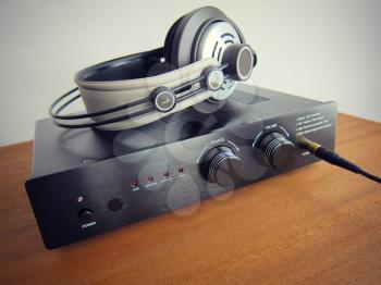 Black DAC Headphone amplifier with connected headphones on the wooden desk