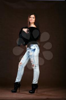 attracive young woman in a fur coat and jeans on browm background