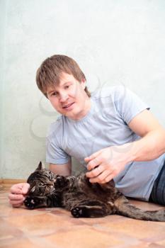 relaxed man lying on the floor with cat against wall