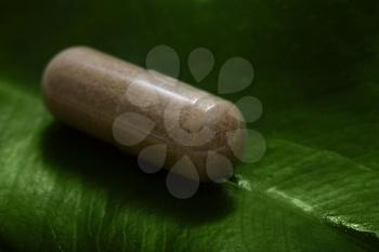herbal medicine - pill on green leaf macro