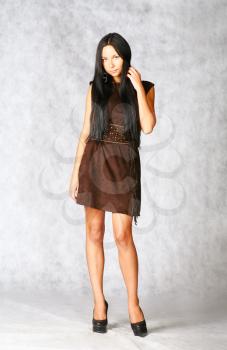 sexy brunette in brown dress on gray background