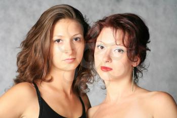 portrait of two sexy girls - redhead and brunette onthe  grey background