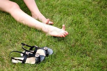 Womans bare feet on the fresh green grass and shoes