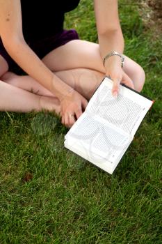 lovely girl reading the book outdoors sitting on the green grass