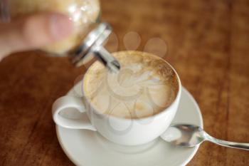 cappuccino cup on the brown wooden table with sugar