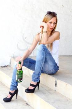 Cute female sitting on the stairs with bottle of vine