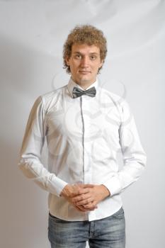 Fashionable boy blank expression. Curly hair, white shirt. Bow tie for something funny