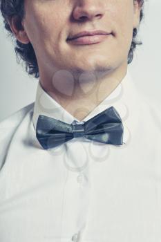 Toned image of the Stylish man in elegant black tuxedo, bow tie closeup and half of the face. Elegance concept.