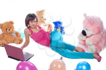Young girl using a laptop near bear toys laying on white studio shot