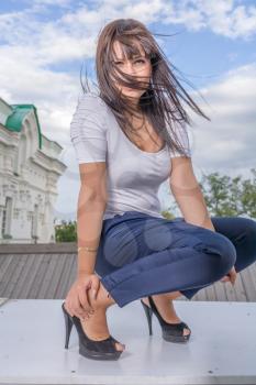 Model posing in front of tall historical building, sitting near