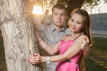 Young couple in love. Portrait of a passionate couple in love embracing near tree sunset backlit