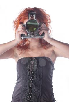Photo of a beautiful female with red hair holding an old film camera.