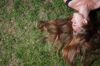 The girl lays on a grass of the meadow. Woman relaxes on the grass. Cute young female lying on grass field at the park.