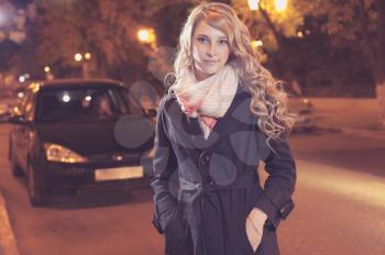 Young blond woman walking on the street, car on background