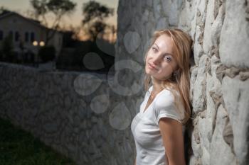 blonde female against wall outdoor and cityscape on background