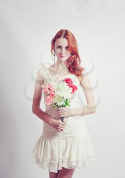Beautiful redheaded girl with flowers, studio shot, toned cross processed colors
