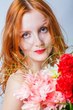 Very closeup shot of the redhead with bunch of flowers in studio on white