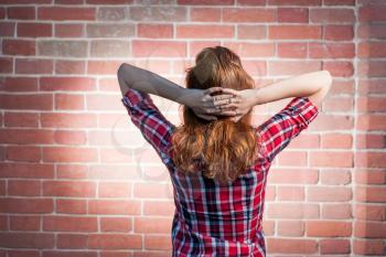 Rear view of a red haired women looking at brick wall with spot light