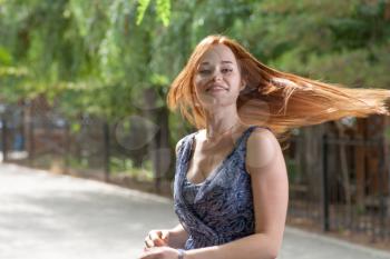 Red haired women dancing outdoors in city park. Her beautyful hair flying in the air. Blurred motion