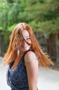 Pretty red haired women posing with her hairs flying in the air