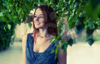 Redhead women smiling in green leaves outdoors.