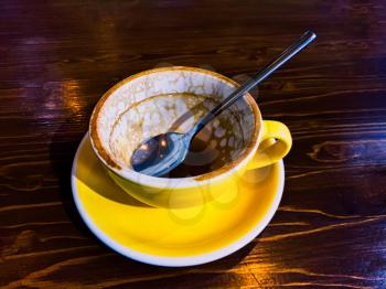 Empty coffee cup with spoon on dark wooden tabletop at coffee shop