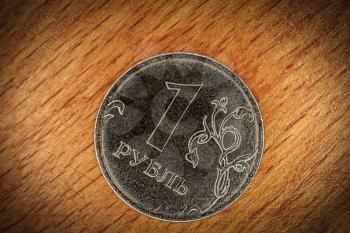 One ruble coin macro on wooden background. Modern Russian currency image with vignette.