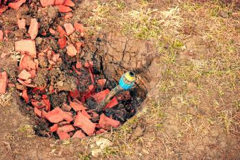 Repair and fixing in yard concept. Broken water pipe in back yard ditch with fragments of red bricks, copyspace