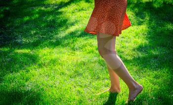 Summertime fun. Bare legs on grass dancing backlit shot.