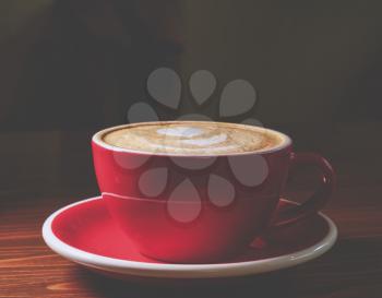 Coffee in red cup on desk, dark background with copyspace