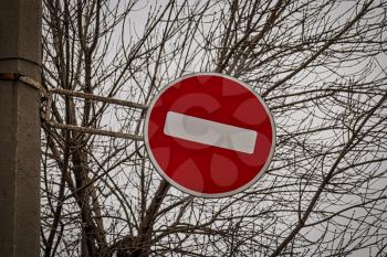 Brohibiting road sign brick set against bare tree branches as a symbol of restrictions in human life