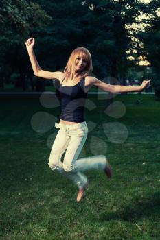 Slim blonde jumping on green grass