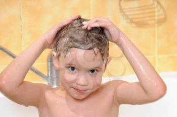 child washing in the shower with a foam on the head 