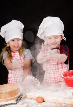 Two children plays with the flour on dark background