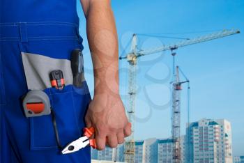 Royalty Free Photo of a Worker Holding a Tool With a Building in the Background