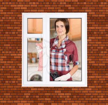 Royalty Free Photo of a Woman Standing by a Window Cleaning