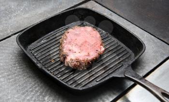 Royalty Free Photo of a Steak Grilling in a Cast-Iron Pan