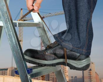 Royalty Free Photo of a Repairman Lacing His Shoes on a Building Background