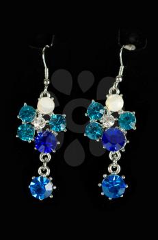 Beautiful earrings with colorful gems on black background
